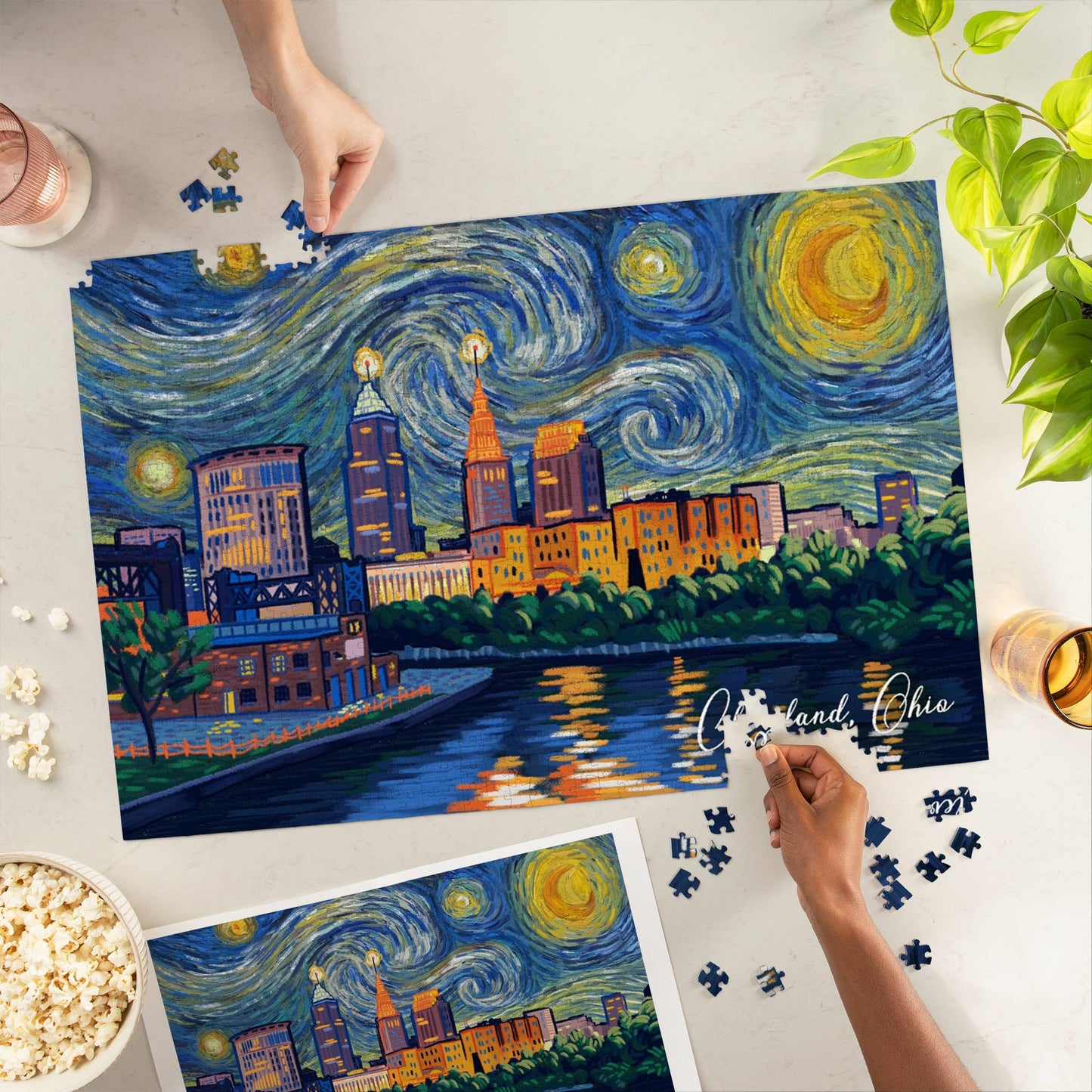 Puzzle of a cityscape with a starry night sky, being completed by hands on a table.