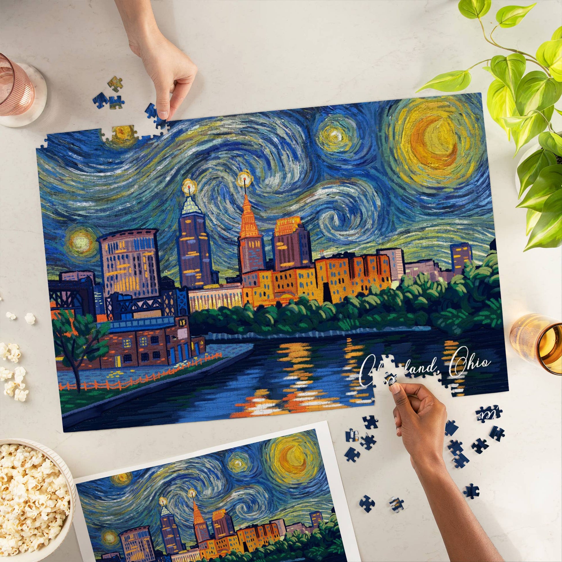 Puzzle of a cityscape with a starry night sky, being completed by hands on a table.