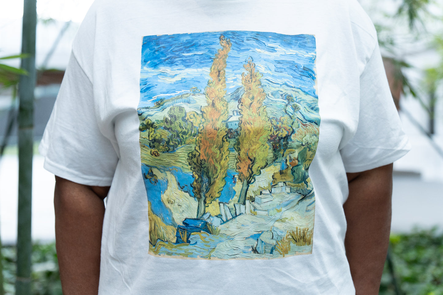 White t-shirt with a Van Gogh-style landscape print on the back, worn by a person.
